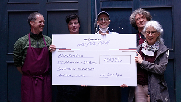Mitarbeiter des Altstadt-Armenküche Düsseldorf e.V. freuen sich über einen Scheck in Höhe von 10000 € von Samsung und der Stiftung "Die-Mannschaft - Wir für euch"